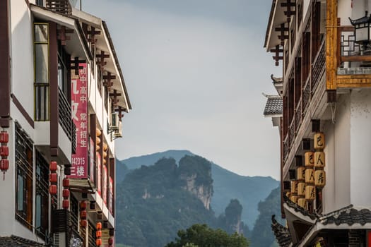 Wulingyuan, China - August 2019 : Windows and balconies of chinese buildings with the stunningly beautiful rocky karst mountain formations behind as seen from the centre of town, Hunan Province
