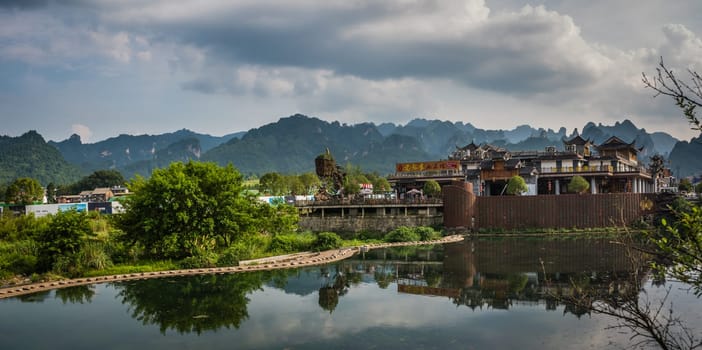Wulingyuan, China - August 2019 : Riverside buildings with the stunningly beautiful rocky karst mountain formations behind as seen from the centre of  town, Hunan Province