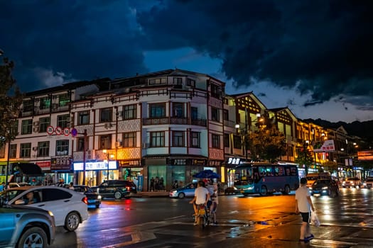 Wulingyuan, China - August 2019 : Bustling life with cars, traffic and lights on buildings lit at night at a busy high street in Wulingyuan town at dusk