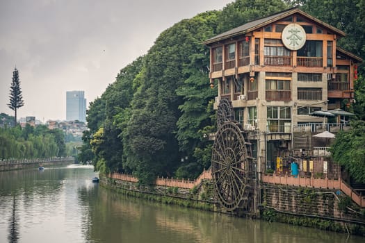 Chengdu, China -  July 2019 : Old mill building with big wooden wheel on the bank of Jin River flowing through Chengdu city, Sichuan Province