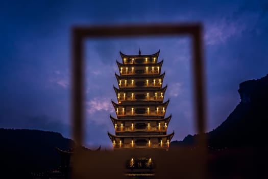 Wulingyuan, China - August 2019 : Framed  at dusk traditional chinese style wooden tower pagoda standing at the Wulingyuan entrance to the Zhangjiajie national park, Hunan Province