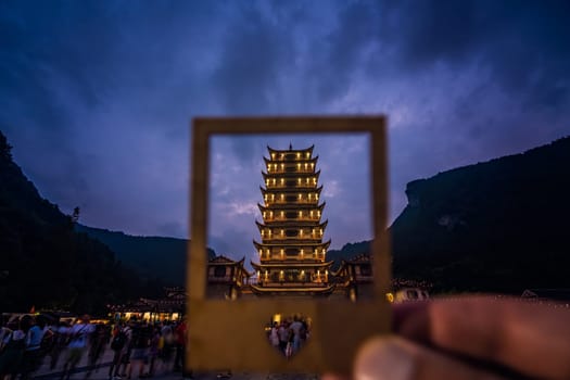 Wulingyuan, China - August 2019 : Framed  at dusk traditional chinese style wooden tower pagoda standing at the Wulingyuan entrance to the Zhangjiajie national park, Hunan Province