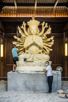 Chengdu, China -  July 2019 :  Male workers creating and restoring large sculpture of multi handed God Shiva in the courtyard of the Buddhist Wenshu Monastery