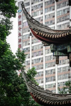 Chengdu, China -  July 2019 : Close up of a traditional chinese building roof in Wenshu Monastery with tall corporate office building in the background