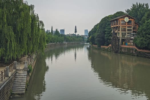 Chengdu, China -  July 2019 : Old mill building with big wooden wheel on the bank of Jin River flowing through Chengdu city, Sichuan Province