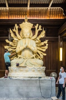 Chengdu, China -  July 2019 :  Male workers creating and restoring large sculpture of multi handed God Shiva in the courtyard of the Buddhist Wenshu Monastery
