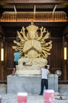 Chengdu, China -  July 2019 :  Male workers creating and restoring large sculpture of multi handed God Shiva in the courtyard of the Buddhist Wenshu Monastery