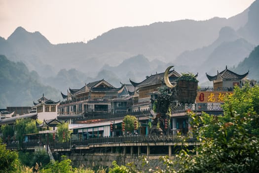 Wulingyuan, China - August 2019 : Rooftops of traditional chinese buildings with the stunningly beautiful rocky karst mountain formations behind as seen from the centre of town, Hunan Province