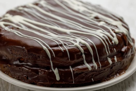 Homemade chocolate cake with chocolate glaze with white stripes on brown