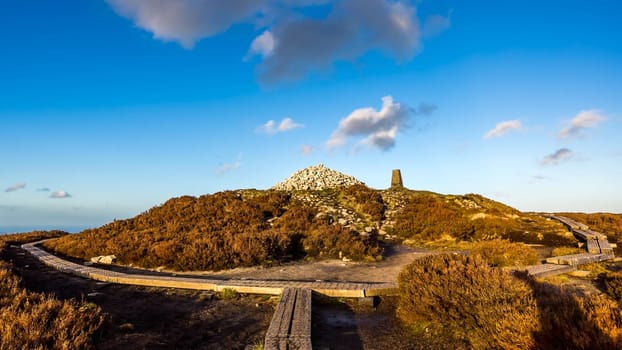 Board walk at Ticknock hill in Wicklow mountains with pile of stones called Fairy Castle, sunset, Ireland