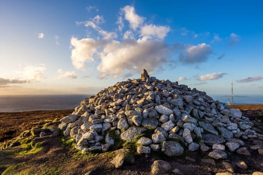 Beautifully sunset at Ticknock hill in Wicklow mountains with pile of stones called Fairy Castle and Dublin bay in background, golden hour, Ireland