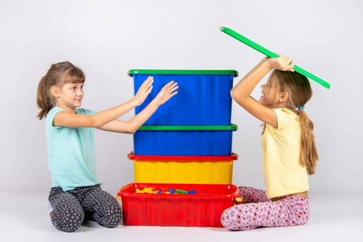 A girl pretending to be a hundred wants to throw a toy box lid on another girl
