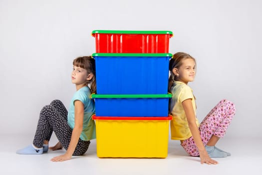 Two girls from different sides leaned their backs on plastic boxes