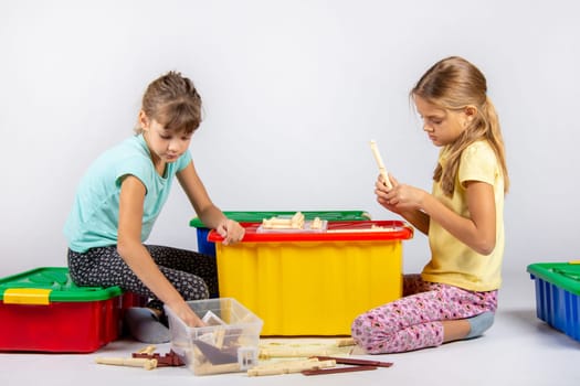 Two girls collect a house from the designer on a large plastic box