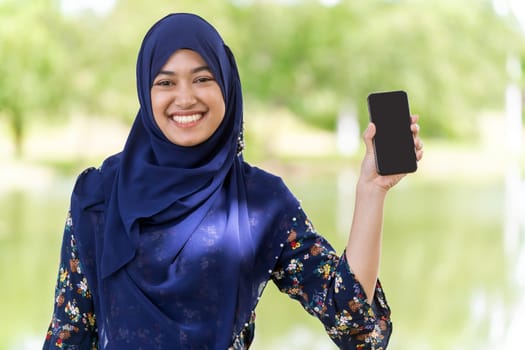 Portrait of good-looking Happy young teenager Muslim islamic asian university girl hold mobile phone