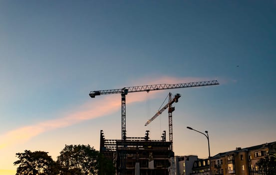 Construction cranes on a sunset background. Construction and repair. City landscape. Place for text.