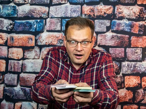 A man with glasses is surprised at the money in his hands. Delight. The salary.