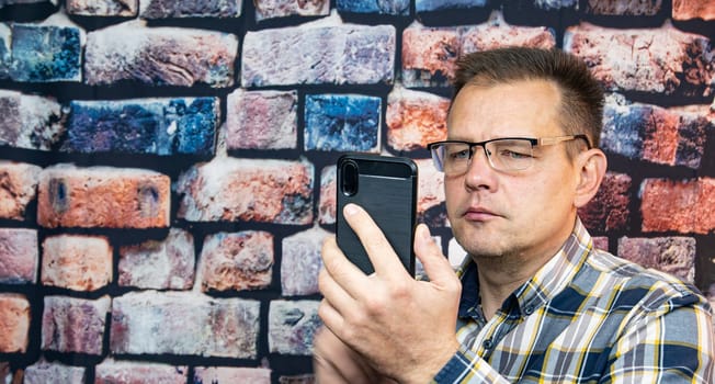 A man in glasses with a mobile phone in his hand. People. Technologies.