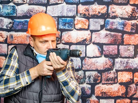 A man with a drill on the background of the wall. Working. Profession.