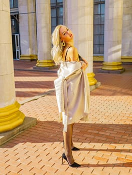 Blonde girl on a background of white columns of a building. Model photo. Women.