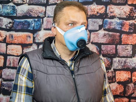 A man in a respirator against the background of the wall. Working. Profession.