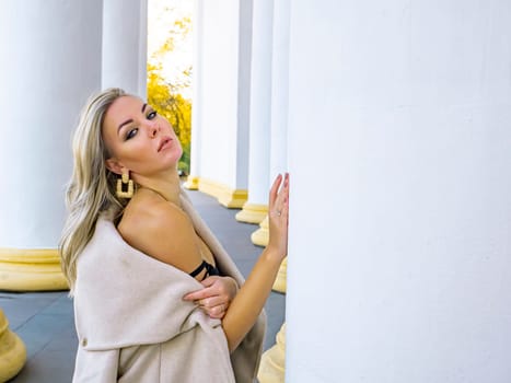 Blonde girl on a background of white columns of a building. Model photo. Women.