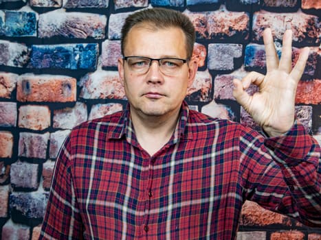 A man with glasses shows a hand gesture ok. Signs and symbols. People.
