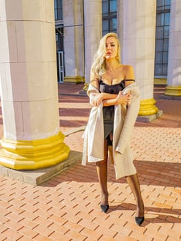 Blonde girl on a background of white columns of a building. Model photo. Women.