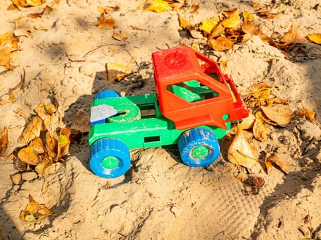 Children's plastic toy lorry in the sand. Children's games.