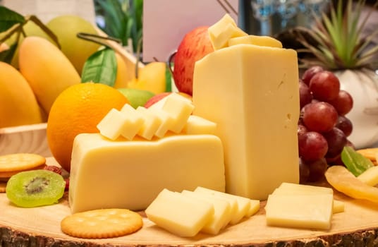 edam cheese with variety of fruit and cracker on wooden plate in buffet line