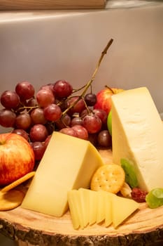 gruyere cheese with variety of fruit and cracker on wooden plate in buffet line