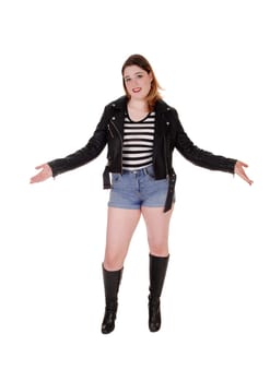 A young pretty woman standing in shorts and boots and a leather.jacket with booth's hands outstretched, isolated for white background.