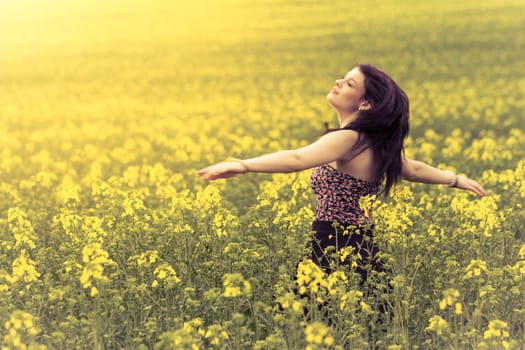 Attractive authentic young girl enjoying the luxury of warm summer sun sunshine and wellbeing youth in wide landscape. Part of series.