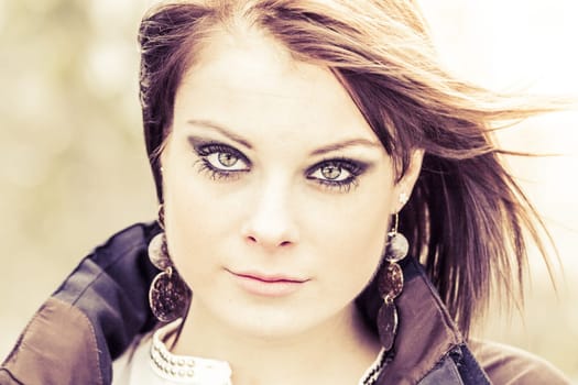 Beauty girl with make-up bright skin look is sexy attractive and serious. Eye shadow earrings and brunette hair in wind. Perfect youth