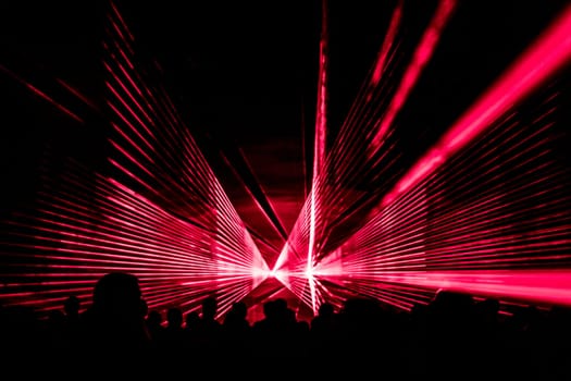 Luxury entertainment with audience silhouettes in nightclub event, festival or New Year's Eve. Beams and rays shining colorful lights.