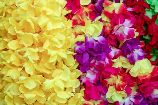 Artificial flowers background. Close-up of nice rainbow-colored petals made of fabric on a beautiful sunny day. Beautiful fresh flower texture for wedding, holidays and other festivals. Card concept.