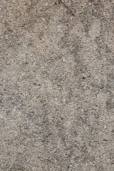 Gray texture of a concrete wall. Closeup of a gray brown of a weathered concrete wall with a hilly uneven surface with small stones. Abstract background concept.