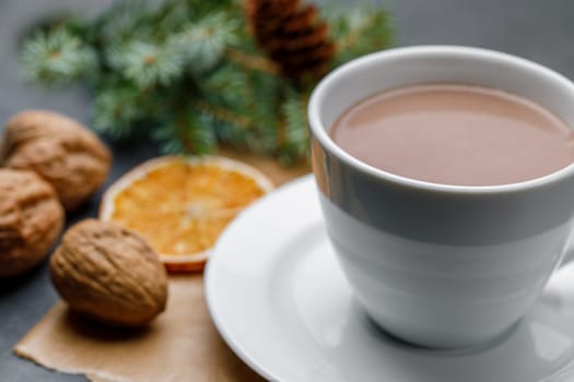 White cup with cocoa on a Christmas background with walnuts, an orange slice, with shallow depth of field