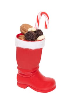 Christmas decorations isolated. Close-up of a red Santa Claus boots filled with nuts and other sweets isolated on a white background. Macro photograph.