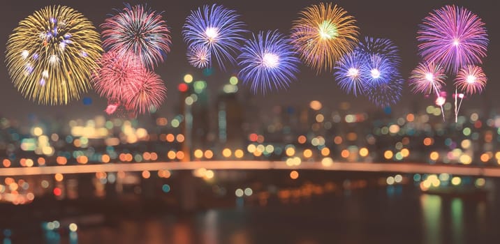 Colorful fireworks on skyline background with blurred city night illuminated lights bokeh