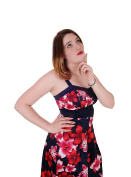 A young dreaming woman in a close up image with her finger on her.chin looking up, isolated for white background.