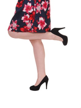 A close up image of the legs of a young woman standing on one leg.only is high heels and dress, isolated for white background.