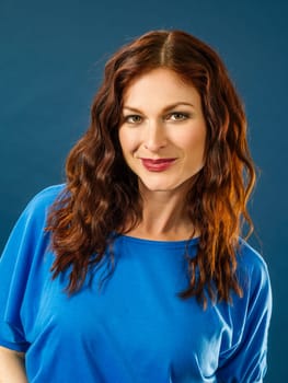 Portrait of a gorgeous woman with red hair over blue background.