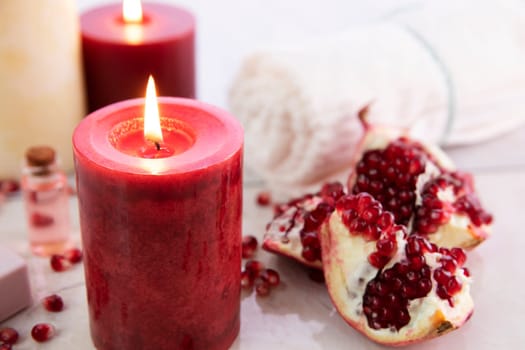 Pomegranate with burning red candle and spa towel