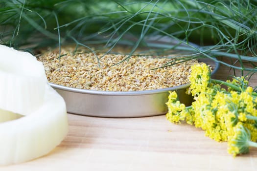 Tin of fennel pollen with flowers and fennel leaves
