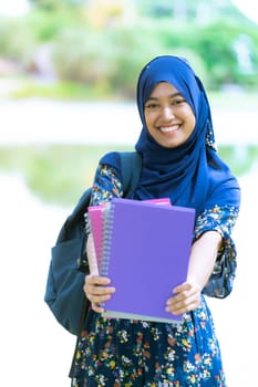 Portrait of good-looking Happy young teenager Muslim islamic asian university girl holding hers books for knowledge and wisdom concept