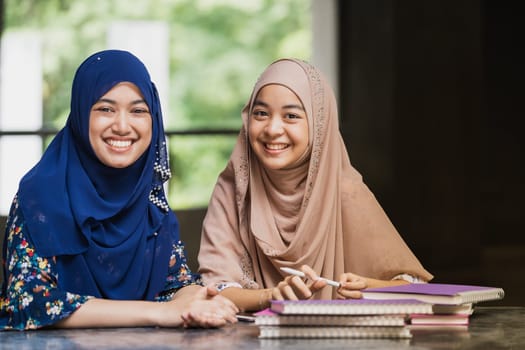 Teenager Young Adult Asian Thai Muslim university college students reading book and using digital tablet together using for education and online education concept