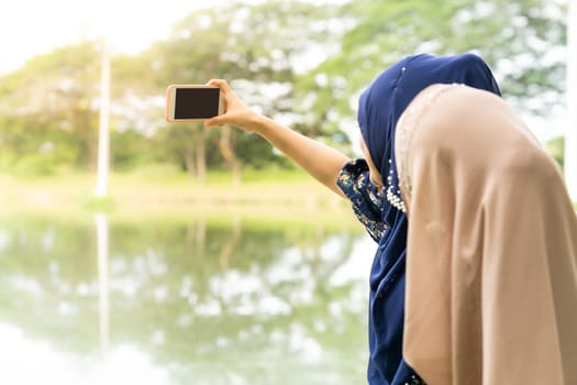 Young adult teenager Muslim Islamic Thai Asian women university students using smartphones to make thier selfie photographing