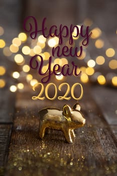 Happy New Year 2020 with a little golden pig in front of Christmas lights