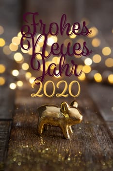Happy New Year 2020 with a little golden pig in front of Christmas lights